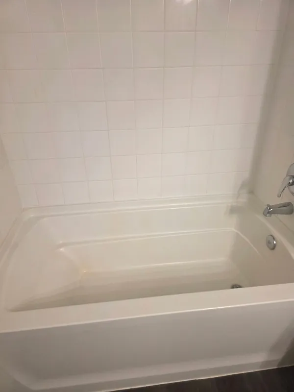 Before: white tub and tile surround with dull residue on the tub floor.